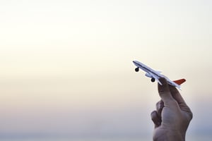 woman-hand-holding-airplane-model-sunset-sky-summer-sea-background